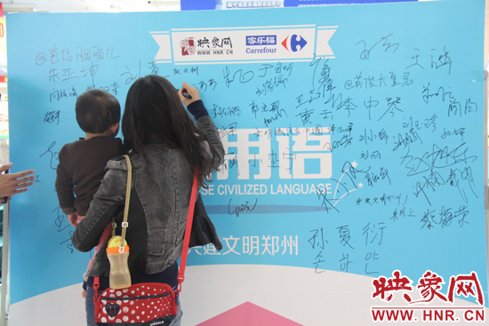 市民在活动签名板上签字支持使用文明用语