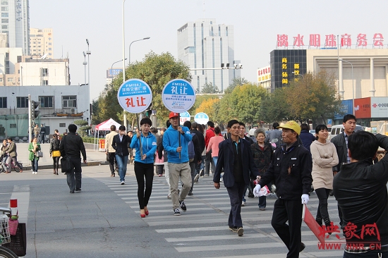 河南交通广播的主持人们引导过马路的行人从斑马线通行