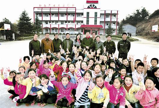 图为：高新民夫妻俩和大畈河希望小学的师生们合影