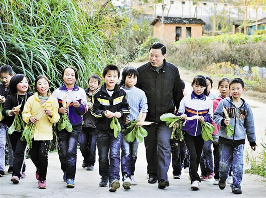 　图为：高新民带着学生们去地里拔萝卜后返回学校