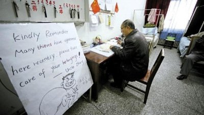 张大爷在门卫室里工作，旁边是红爆网络的温馨提示牌记者