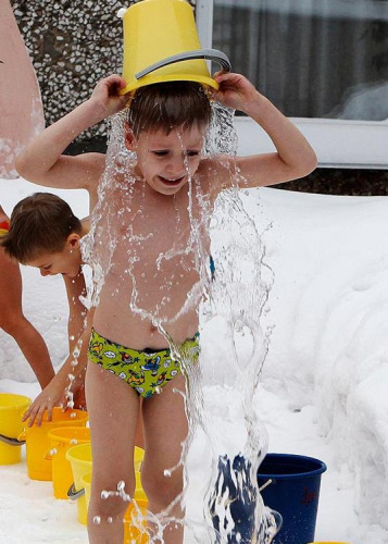 俄罗斯一名男童在雪地冲凉水澡。