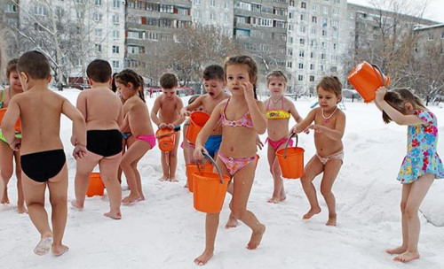 幼儿园的儿童身穿泳装，在零下25度的雪地里冲凉水澡。