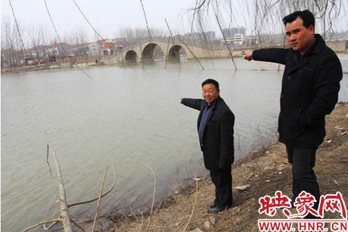 水上义务救援队队员韩明（左一），贾建峰（右一）向记者讲述轿车落水地点