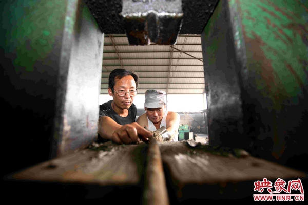 刘金玉正与工友一起用自己发明的综合液压机对废旧锚杆进行轧直处理