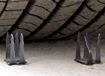 新郑路路边停放的车辆轮胎下被人放置四齿板凳状钉子。