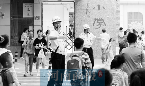 伊河路小学门口，两名巡防队员护送学生过马路