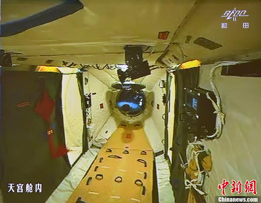 图为在张晓光的协助下，聂海胜顺利开启并进入天宫一号舱门。