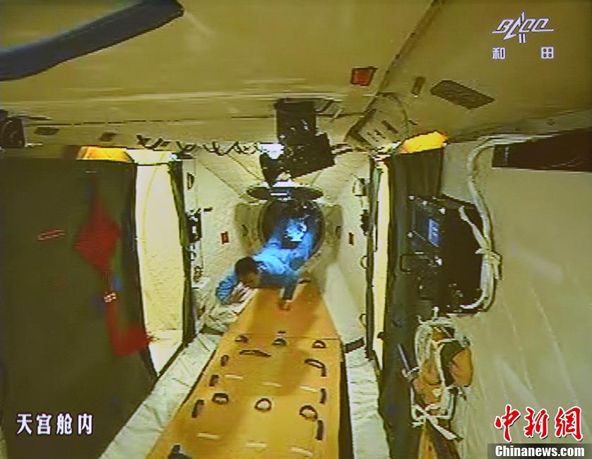 图为在张晓光的协助下，聂海胜顺利开启并进入天宫一号舱门。
