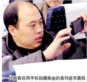 一位旅客在用手机拍摄乘坐的首列进京高铁
