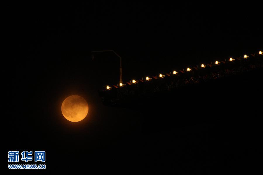 6月23日晚，北京上空的圆月与建筑物上的灯光相互映衬。
