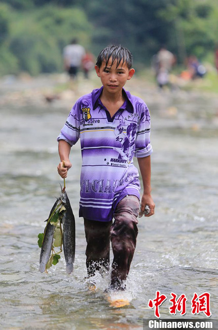 图为7月9日，一名男孩在闹鱼节活动中抓到了两条鱼。谭凯兴 摄