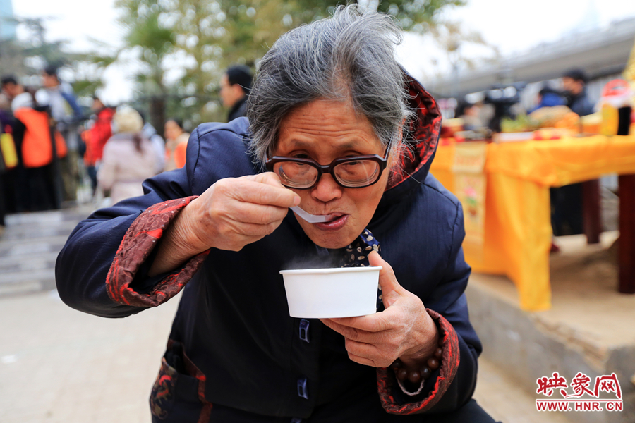 紫荆山施粥点老奶奶领到热腾腾的腊八粥后马上品尝起来