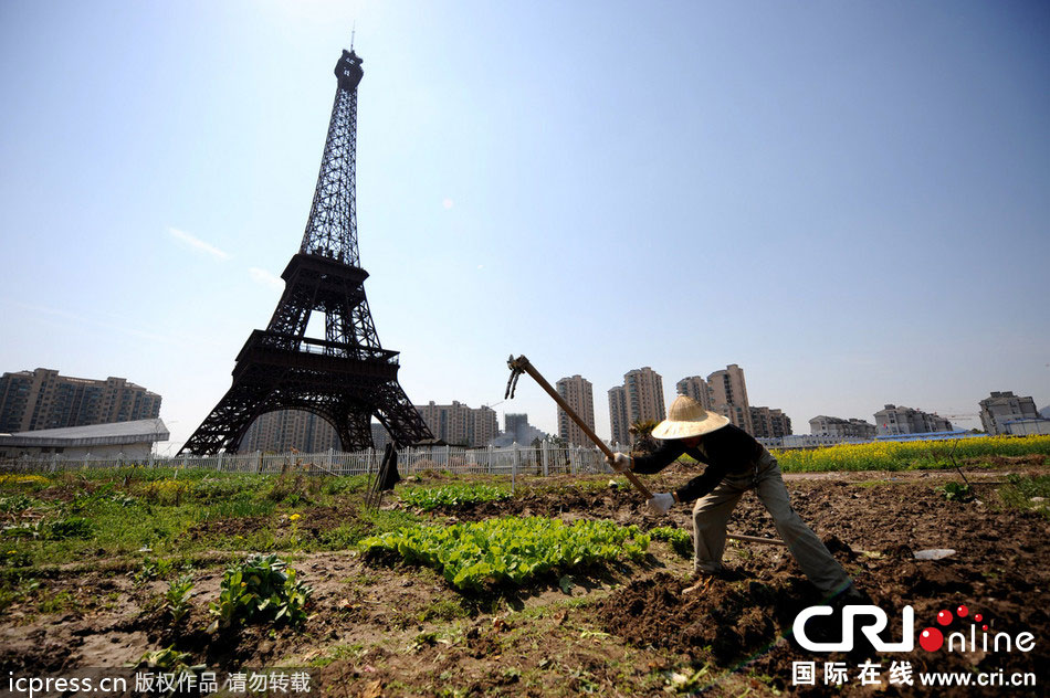 　2014年3月21日，杭州天都城，农民在山寨埃菲尔铁塔下耕作。图片来源：东方IC