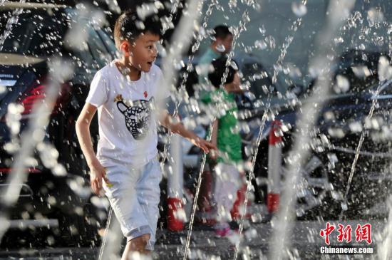 山西太原最高温36℃,儿童在喷泉周围戏水消暑。