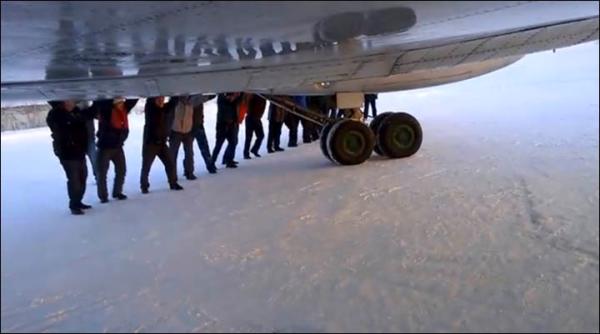 　伊加尔市一架客机起飞前被冻在了跑道上。飞机上的乘客不得不下来推飞机。