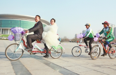 气球和鲜花装点的双人自行车，新郎郝幸福载着美丽新娘回家。