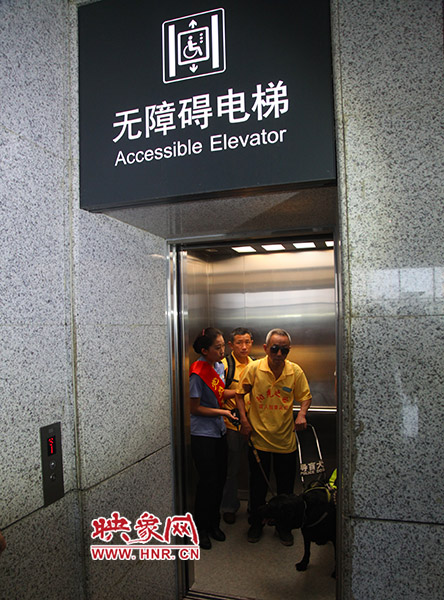 视力残障人士在工作人员引导下乘坐无障碍电梯
