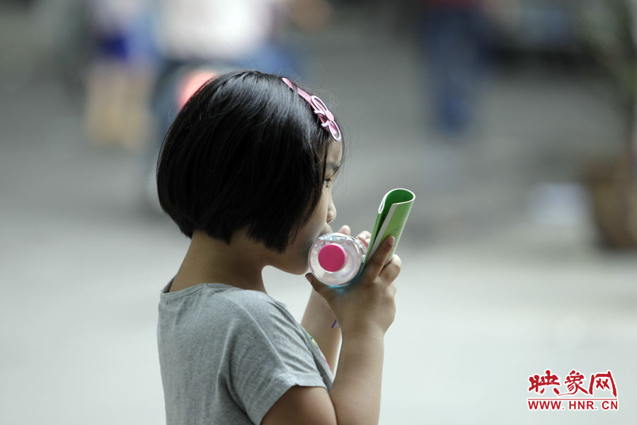 6月7日，郑州回中考点，一名孩子拿着一瓶矿泉水，等待哥哥走出考场