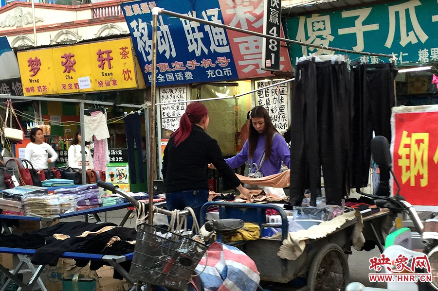 街道的摊位前一位女士正在买衣服
