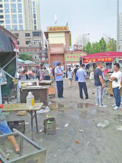 昨天，执法人员在京广路长江路口整治“僵尸围挡”及围挡内的摊贩。