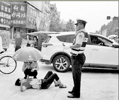 老太被撞倒地 漯河交警烈日下撑伞救援