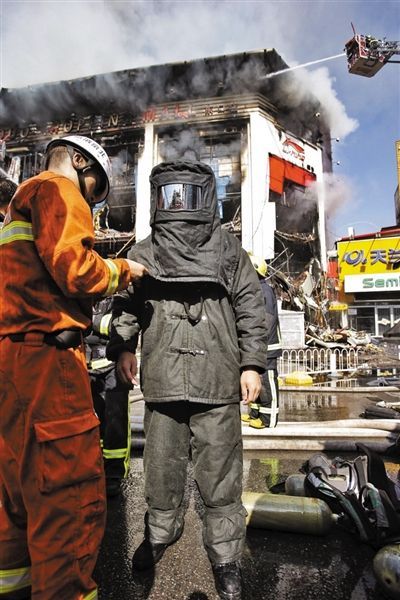 11日，消防战士穿着隔热服装准备进入商场灭火。