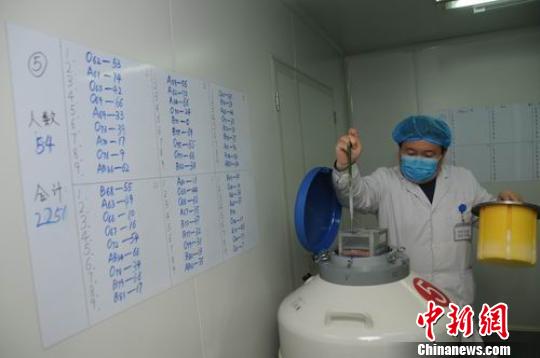 　山西省人类精子库冷冻室内，工作人员查看从液氮罐中取出装着精子的试管。　武俊杰　摄