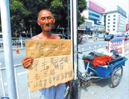 老人举着牌子在路边等候失主。京华时报记者谭青摄