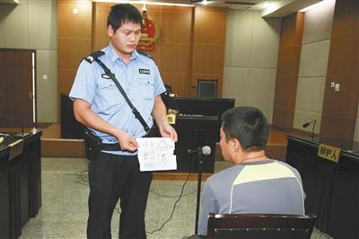昨日庭审中，法警向赵某出示其扎完车胎后所留辱骂公司的纸条。通讯员 李秀文 摄