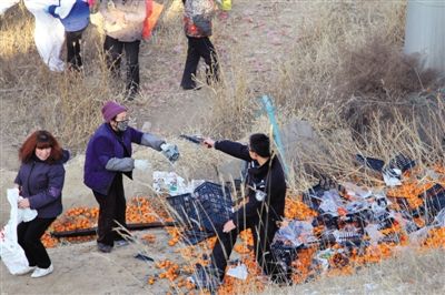 1月4日，连霍高速兰州市榆中县和平镇段，一名警察举着枪驱散哄抢橘子的村民。图/CFP