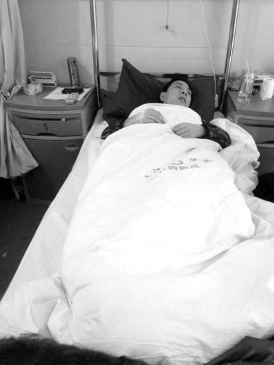 当事人徐世涛躺在垫江县中医院的病床上，由于腰椎和肋骨骨折，他难以翻身，只能长时间平躺。京华时报记者 张剑 摄