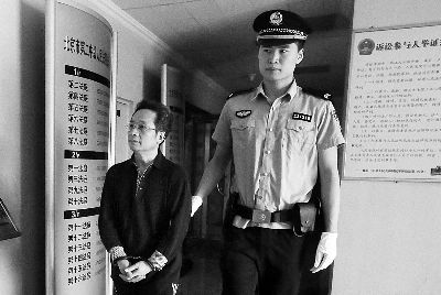 被告人曹建平看见记者面向墙壁躲镜头
