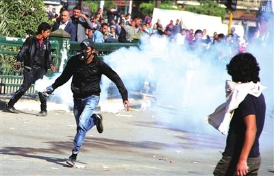 25日，埃及首都开罗解放广场，在与警察对峙时，一名抗议者拾起催泪瓦斯跑开。