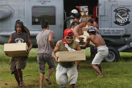 菲律宾难民从美国军用直升机上搬下救援物资。