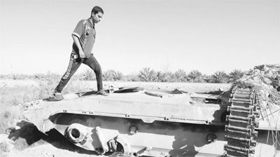 图为在伊拉克卡尔巴拉，一名男子站在伊战时被美军摧毁的伊拉克坦克上。