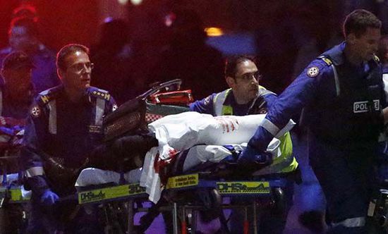 悉尼劫持案现场警方两度与劫持者交火，人质被陆续救出，一名伤员被抬离现场，担架上还有血迹。