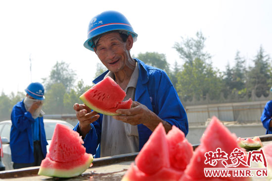 图为一名农民工拿着香甜的西瓜，露出了开心的笑容。