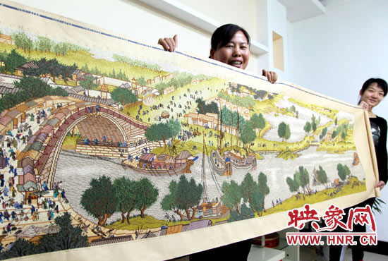 10月31日,河南省宝丰县市民朱学敏(左一)与邻居们一起展示绣成的《清明上河图》。