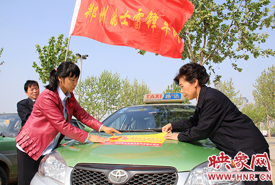 　　授旗结束后，首都的士雷锋车队王凤进队长（右）与郑州的的哥的姐在车身上贴上标识。