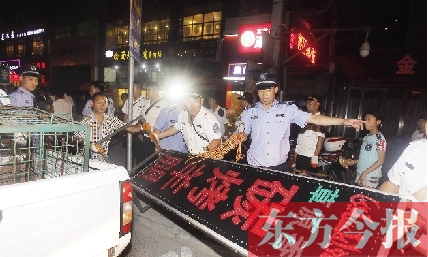 7月8日晚，郑州市商城路一家占道经营的摊贩招牌被执法队员“登记保存”