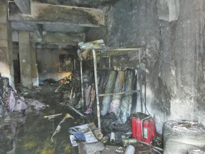 仓库过火后的余灰和灭火用水混在一起，现场一片泥泞。