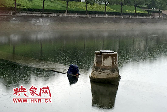 一女子穿着雨披独自站在东风渠中