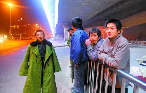 冬夜里，农民工在桥下等着干活儿。