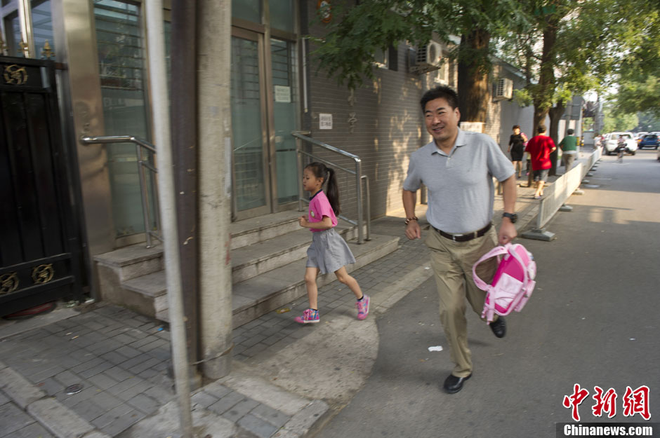 9月2日，一名即将要迟到的小学生在家长的护送下跑步将孩子送来学校。中新社发 崔楠 摄