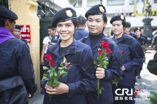2013年12月03日,曼谷总理府与曼谷警署允许反政府示威民众进入,双方进入暂时“停战”状态迎接泰王生日。曼谷警察总署,女警们手持鲜花送给反政府示威民众。图片来源:万家/cfp 　　