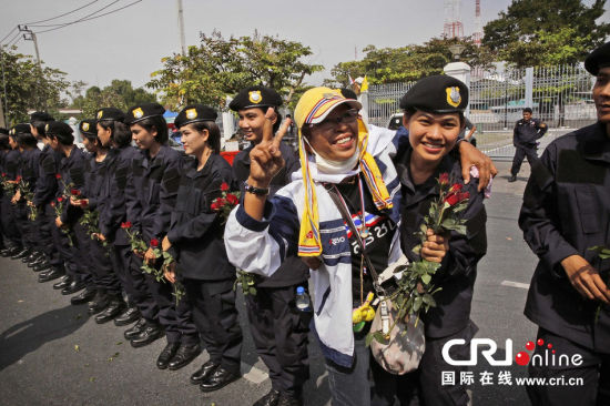 2013年12月03日,曼谷总理府与曼谷警署允许反政府示威民众进入,双方进入暂时“停战”状态迎接泰王生日。曼谷警察总署,女警们手持鲜花送给反政府示威民众。图片来源:Manish Swarup/东方IC