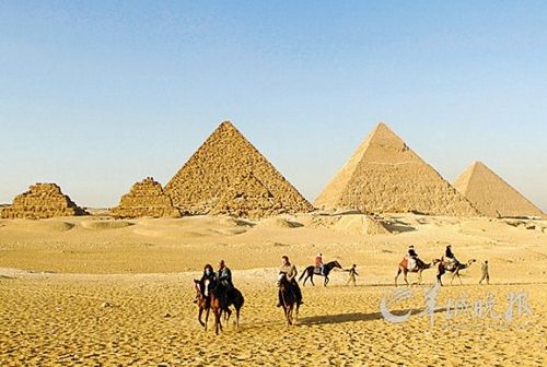 　　埃及首都开罗郊区的吉萨金字塔群,游客骑着马和骆驼在游览。蔺以光 摄