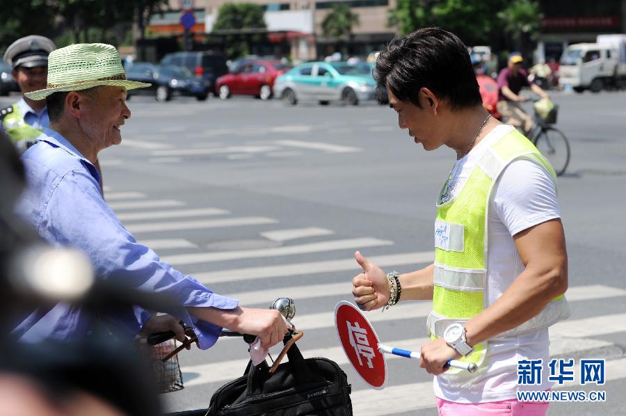 6月17日，任贤齐（右）在杭州街头做交通协管员，向一位遵守交通规则的市民竖起了大拇指。