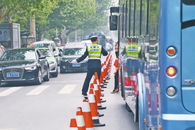 省人民医院南门的路中间摆放反光锥，交警示意由西向东车辆从前方绕行。